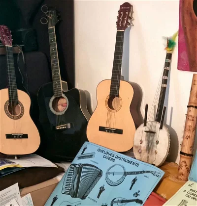 Outils d’Éveil Musical:
- Guitares & Kora
- Affiches de divers instruments inaccessibles: Vents, Percussions, autres Cordes.
Tout de noir vêtue, la brave et célèbre électro-acoustique folk du Maestro Jimmy Curtis.